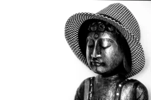 Boeddhabeeld met gesloten ogen en geruite hoed op effen witte achtergrond